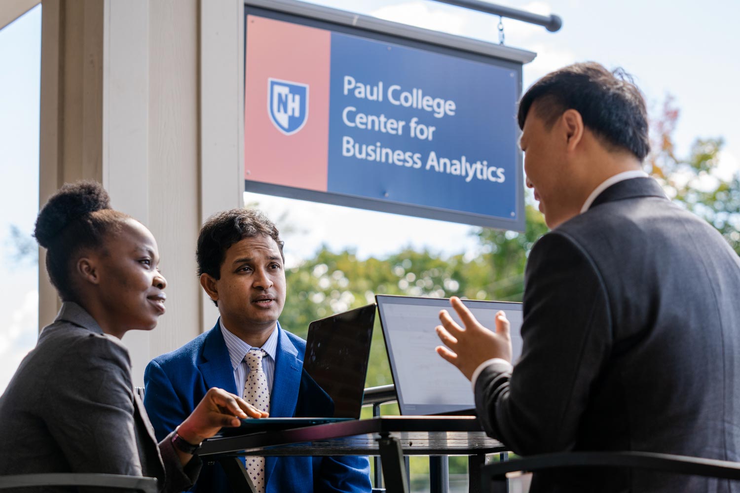 Three colleagues talking outside in front of Paul College Center for Business Analytics