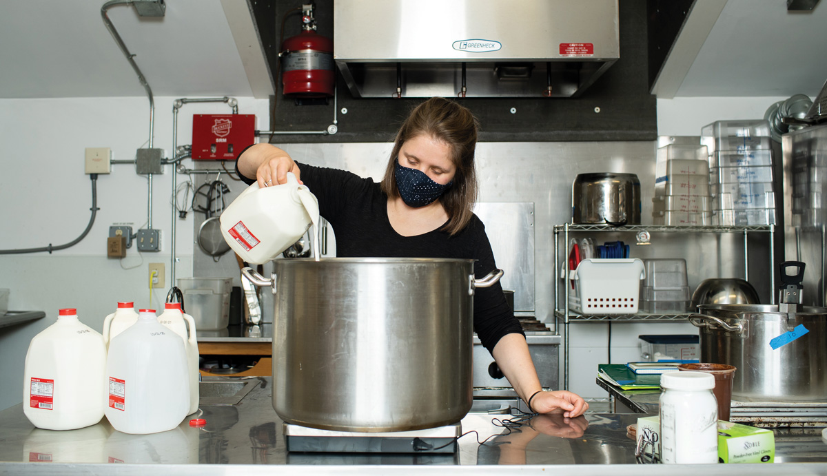 Female student in kitchen pouring milk into large container